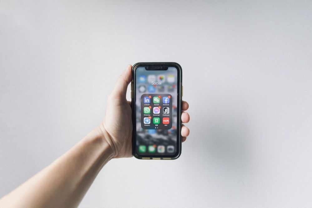 A hand holding a smartphone showing a clean mobile app interface