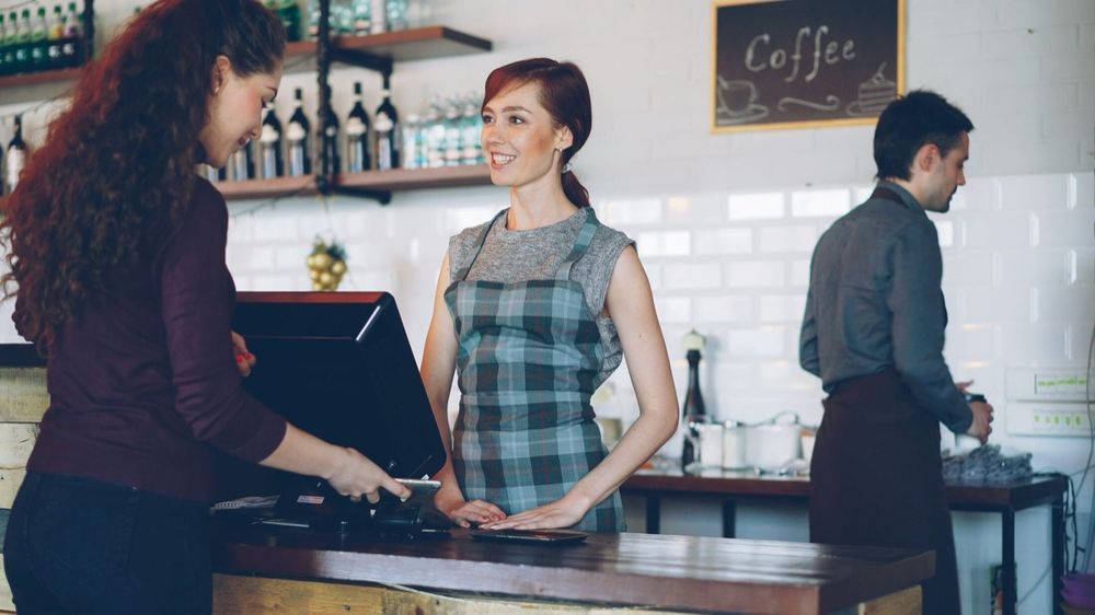 Smiling café staff serving a returning customer at the counter