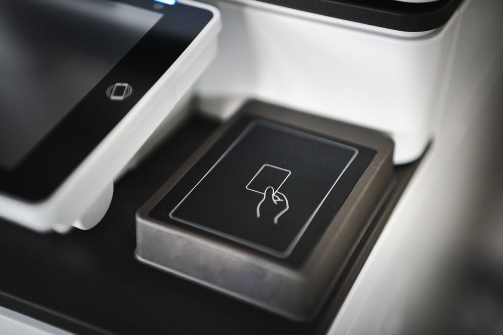 A sleek contactless card payment terminal with the tap-to-pay icon